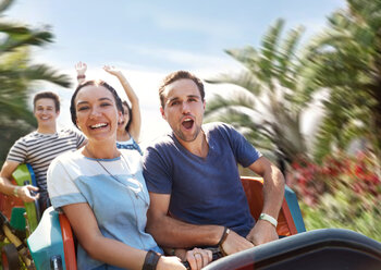 Young couple cheering on amusement park ride - CAIF11300