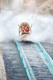 Begeisterte Freunde, die jubeln und auf einer Wasserbahn im Vergnügungspark fahren - CAIF11335