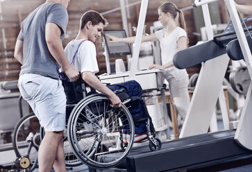 Physiotherapeuten führen Mann im Rollstuhl auf dem Laufband - CAIF11350