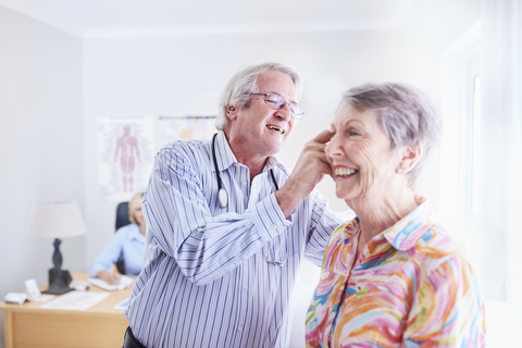 Arzt untersucht das Ohr einer älteren Frau bei einem Checkup, lizenzfreies Stockfoto
