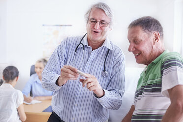 Arzt zeigt älteren Mann digitales Thermometer bei der Untersuchung - CAIF11380