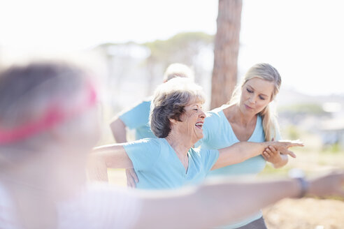 Yogalehrerin führt ältere Frau im sonnigen Park - CAIF11388