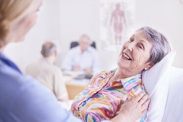 Arzt tröstet lächelnde ältere Frau bei der Untersuchung - CAIF11393