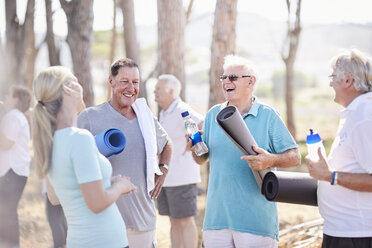 Yoga-Lehrer im Gespräch mit älteren Männern nach dem Unterricht im Park - CAIF11397