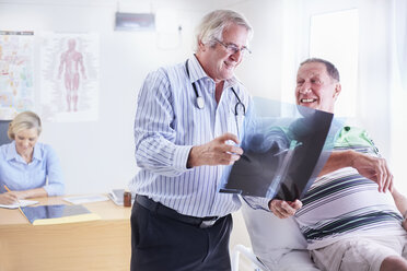 Arzt zeigt älteren Mann Röntgenbild - CAIF11398