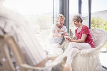 Ältere Frauen telefonieren auf der Terrasse - CAIF11410