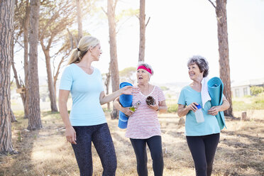 Yogalehrer im Gespräch mit älteren Frauen nach einer Yogastunde im Park - CAIF11411