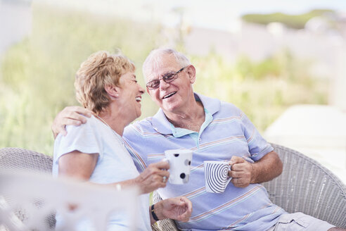 Älteres Paar, das sich umarmt und auf der Terrasse Kaffee trinkt - CAIF11414