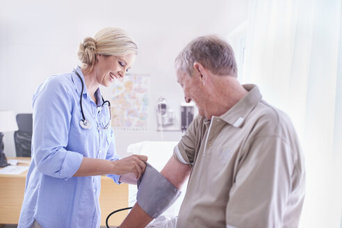 Arzt kontrolliert den Blutdruck eines älteren Mannes im Untersuchungsraum - CAIF11418