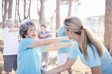 Yoga instructor guiding senior woman in park - CAIF11422