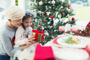 Lächelnde Mutter und Tochter mit Weihnachtsgeschenk - CAIF11424