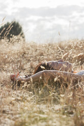 Gelassene Frau, die in einem sonnigen ländlichen Feld schläft - CAIF11468