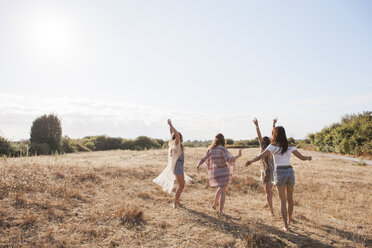 Carefree boho women dancing in sunny rural field - CAIF11474