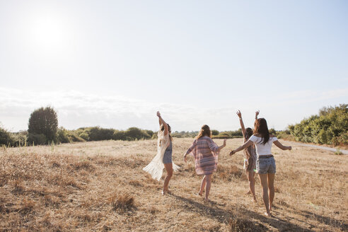 Unbekümmerte Boho-Frauen tanzen auf einem sonnigen ländlichen Feld - CAIF11474