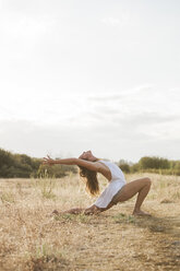 Boho Frau in hohen Halbmond Ausfallschritt Yoga-Pose in sonnigen ländlichen Feld - CAIF11476