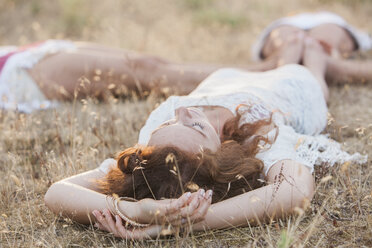 Boho Frauen im Kreis liegend mit Füßen berühren in ländlichen Feld - CAIF11483