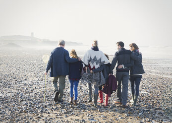 Mehrgenerationen-Familie, die in einer Reihe am Strand spazieren geht - CAIF11486