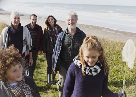 Mehrgenerationenfamilie beim Spaziergang auf dem grasbewachsenen Strandweg - CAIF11487