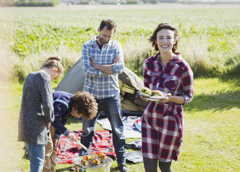 Portrait smiling family barbecuing at sunny campsite - CAIF11491