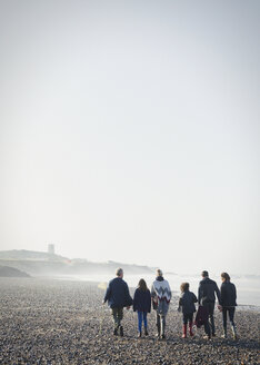 Mehrgenerationenfamilie beim Spaziergang am sonnigen Strand - CAIF11497