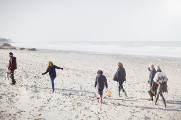 Multi-generation family walking on sunny beach - CAIF11498