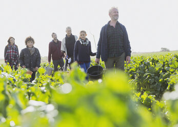 Mehrgenerationenfamilie beim Spaziergang im sonnigen Gemüsegarten - CAIF11500