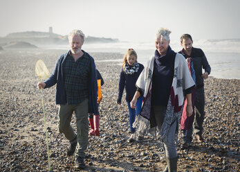 Mehrgenerationenfamilie beim Spaziergang am sonnigen Strand - CAIF11501