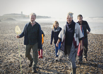 Multi-generation family walking on sunny beach - CAIF11501