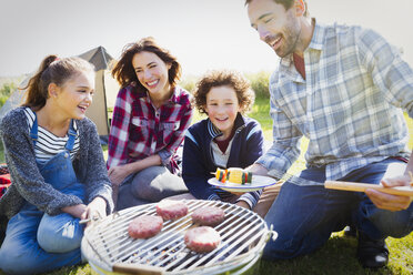 Family barbecuing at sunny campsite - CAIF11502