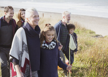 Smiling multi-generation family walking in beach grass - CAIF11506