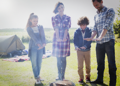 Familie wärmt sich die Hände am Lagerfeuer, lizenzfreies Stockfoto