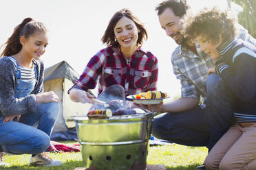 Family barbecuing at campsite grill - CAIF11519