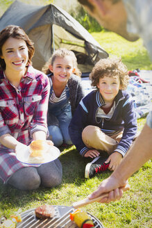 Familie beobachtet Vater beim Grillen auf dem Campingplatz - CAIF11520