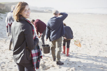 Portrait smiling woman walking on sunny beach with family - CAIF11534