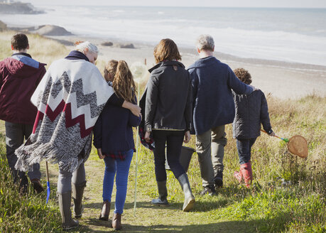 Mehrgenerationenfamilie bei einem Spaziergang auf dem sonnigen Grasstrandweg - CAIF11535