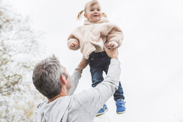 Father lifting toddler daughter overhead - CAIF11538