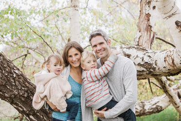 Portrait smiling family in front of tree - CAIF11539