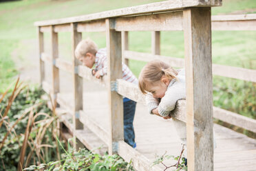 Kleinkinder, die sich auf dem Geländer einer Fußgängerbrücke im Park abstützen - CAIF11546