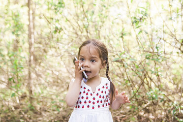 Mädchen im Kleinkindalter, das im Park mit einem Handy telefoniert - CAIF11551