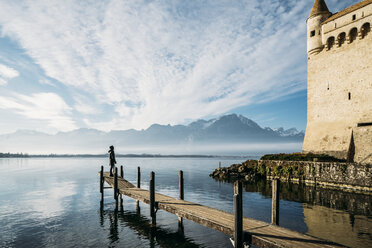 Mann auf einem sonnigen Steg am Seeufer vor dem Schloss Chillon, Schweiz - CAIF11585