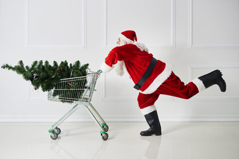 Weihnachtsmann transportiert Weihnachtsbaum in einem Einkaufswagen - ABIF00106