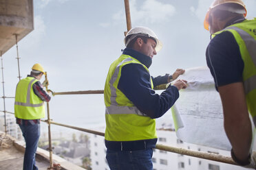 Bauarbeiter und Ingenieur bei der Überprüfung von Bauplänen auf einer Hochhausbaustelle - CAIF11595