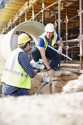 Construction workers talking at construction site - CAIF11597