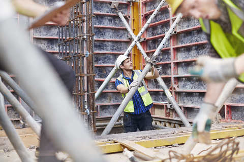 Bauarbeiter bei der Prüfung eines Bauwerks auf der Baustelle, lizenzfreies Stockfoto