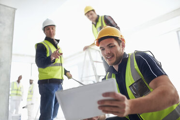 Construction workers with digital tablet at construction site - CAIF11619