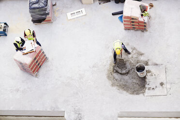 Overhead view of construction workers laying concrete at construction site - CAIF11628