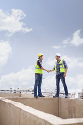 Bauarbeiter beim Händeschütteln auf der Hochhausbaustelle - CAIF11632