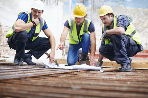 Construction workers and engineer reviewing blueprints at construction site stock photo