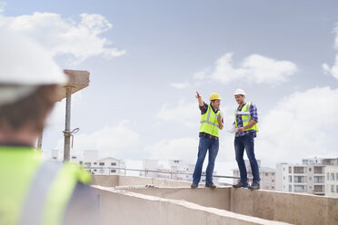 Construction worker and engineer talking at highrise construction site - CAIF11636