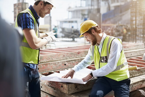 Bauarbeiter und Ingenieur bei der Überprüfung von Bauplänen auf der Baustelle - CAIF11637